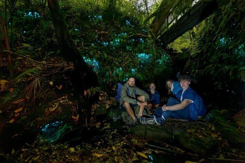 A group of people sitting on a rock in a forested area with blue lights. 2