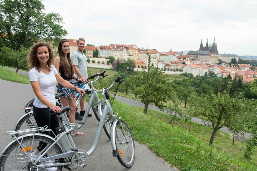 Three people on bicycles with a historic cityscape in the background. 2