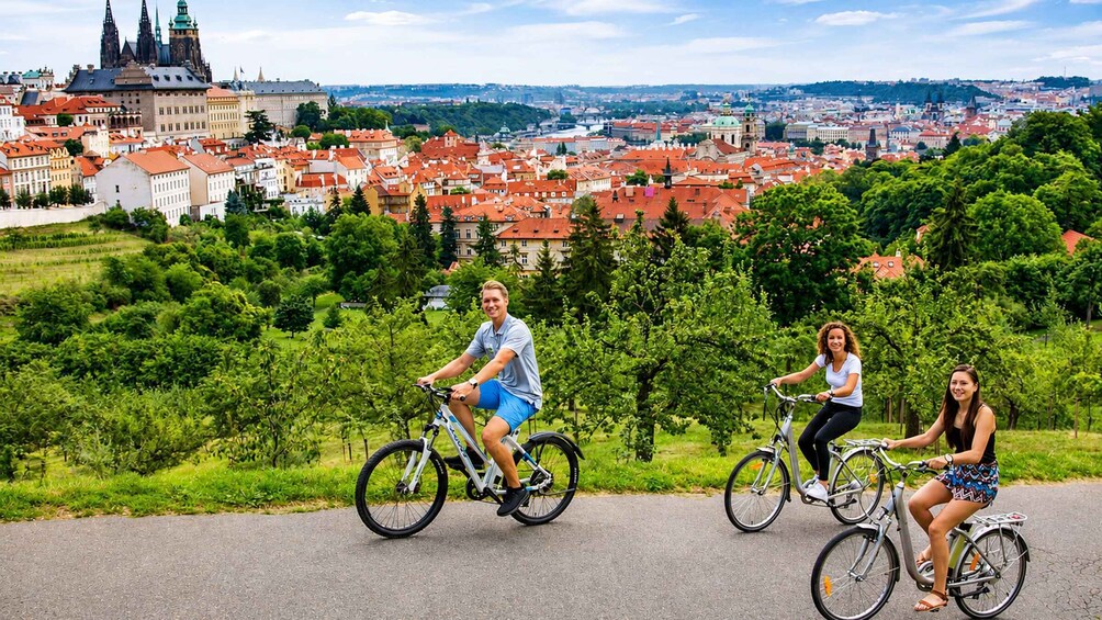 Three people cycling on a road with a cityscape in the background. 2