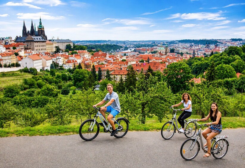 Three people cycling on a road with a cityscape in the background. 2