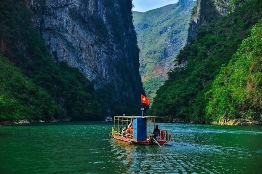 A boat with a flag on a river surrounded by cliffs. 3