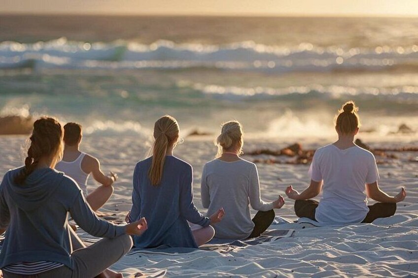 Un grupo de personas meditando en una playa arenosa con el océano al fondo. 4
