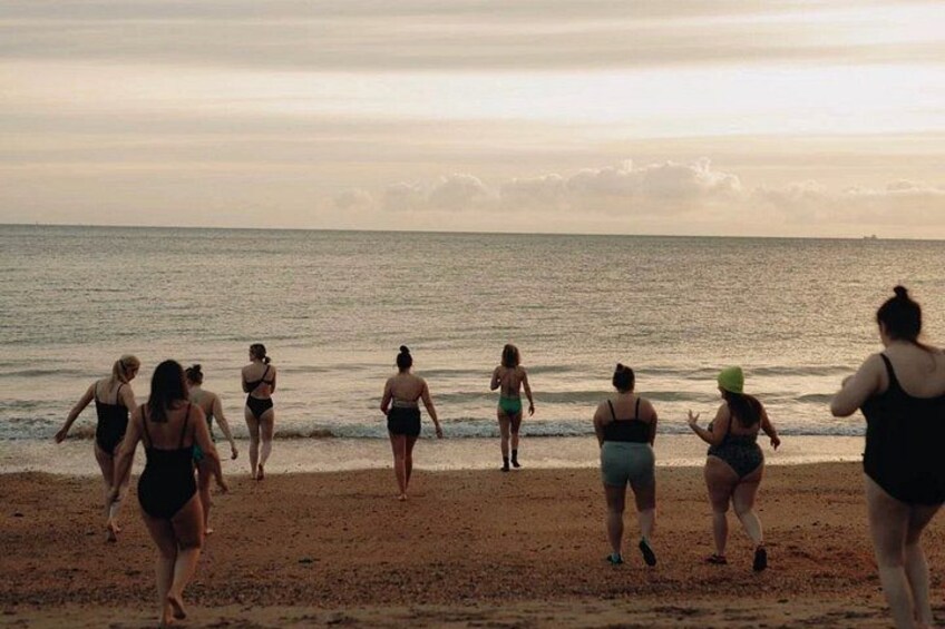 Un grupo de personas caminando por la playa al atardecer. 5