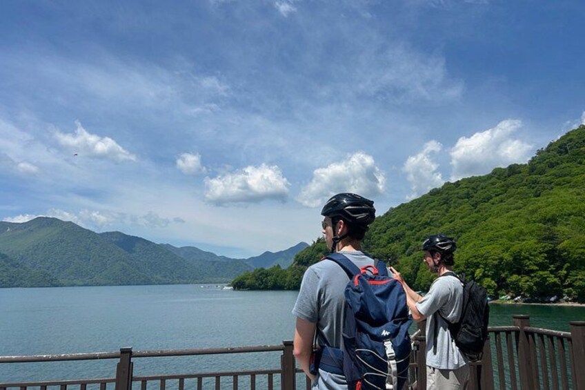 Two people on a bridge overlooking a lake with mountains in the background. 3