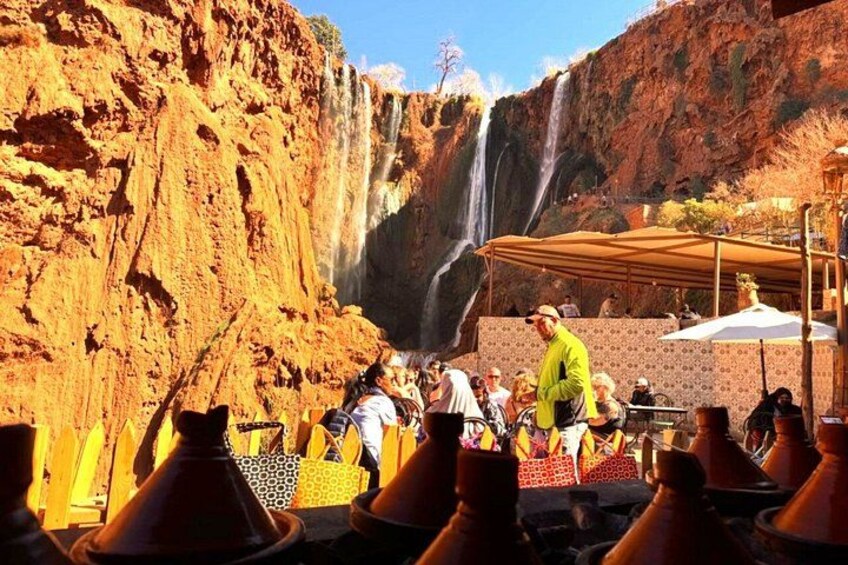 En grupp människor på en turistplats med ett vattenfall och en brant klippa. 2