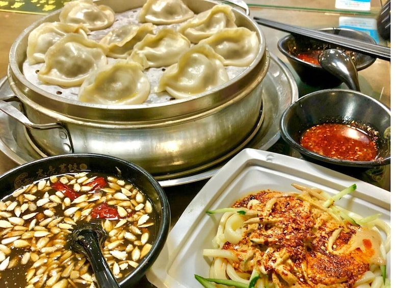 A variety of Asian dishes including dumplings, a spicy dipping sauce, and a noodle dish with sesame seeds. 5
