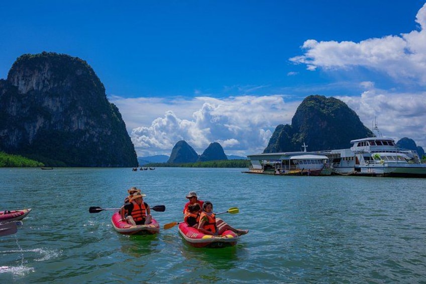 People kayaking on a calm river with large limestone cliffs in the background. 5