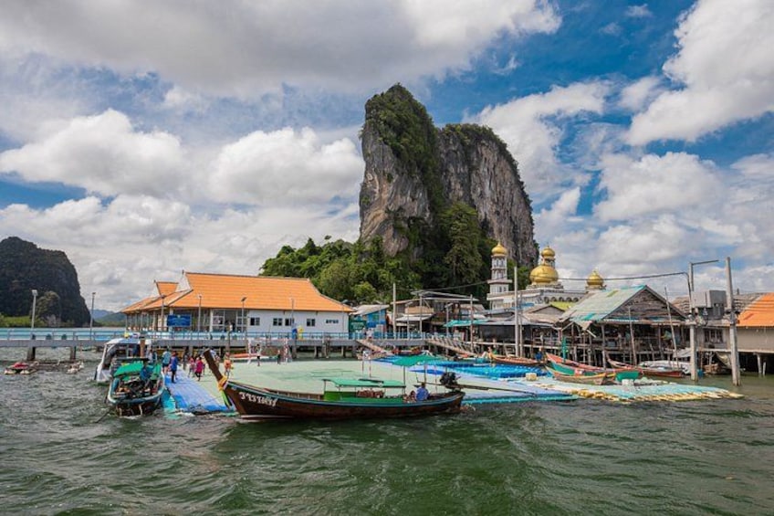 A coastal scene with boats, a pier, and a large rock formation. 3