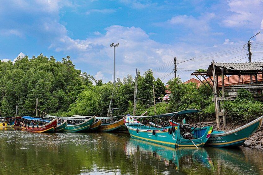 A calm river with several colorful boats docked along the shore, surrounded by lush greenery and a clear sky. 1
