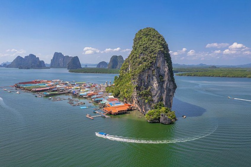 A coastal town with a prominent limestone island, boats, and a clear blue sky. 4