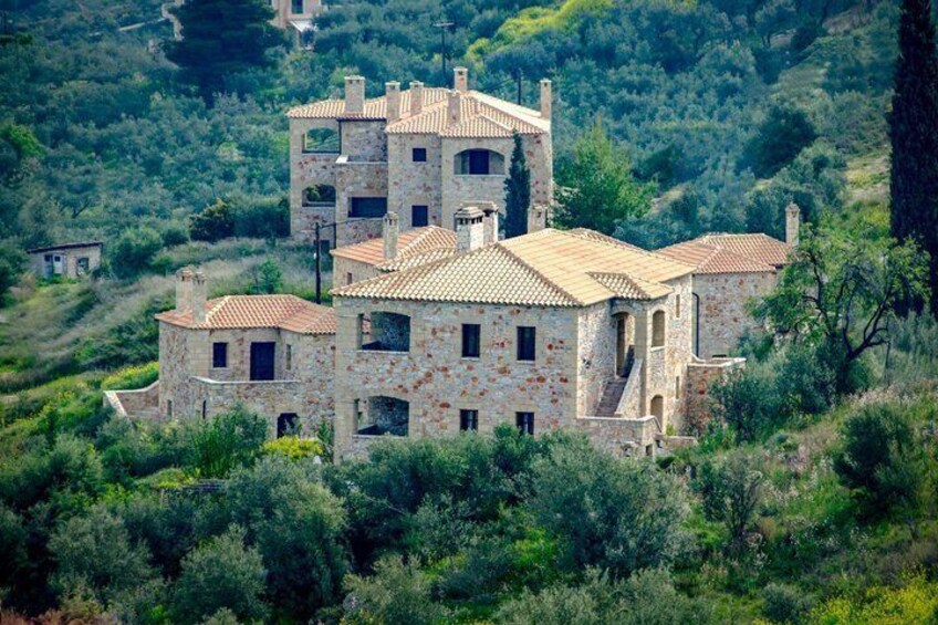 Una casa in pietra con tetto in tegole circondata dal verde. 2