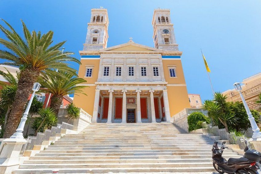 A grand building with two towers, a staircase leading up to the entrance, palm trees, and a flag. 4