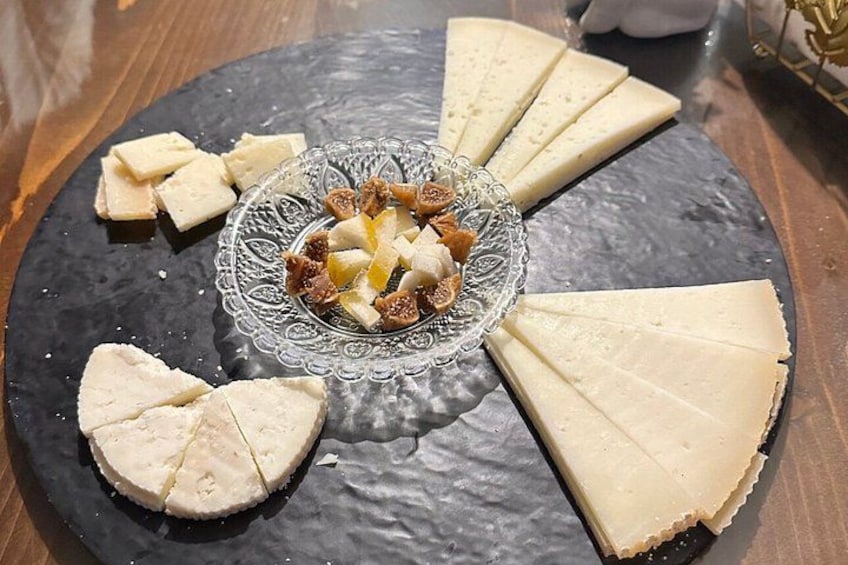 Una tabla de quesos con diferentes tipos de queso y frutas secas sobre un plato de pizarra. 1