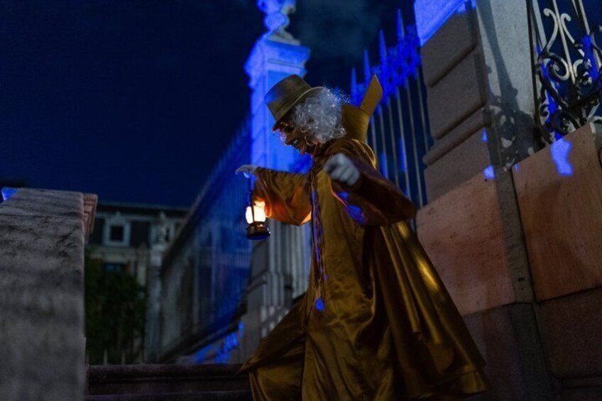 A golden statue of a figure holding a lantern, set against a building with blue lighting. 4