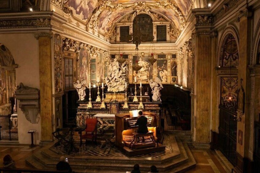 An ornate church interior with a central altar, statues, and intricate ceiling artwork. 1