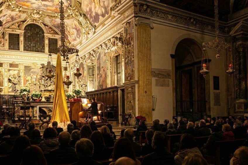 A church interior with ornate decorations, a large golden altar, and a congregation seated. 3