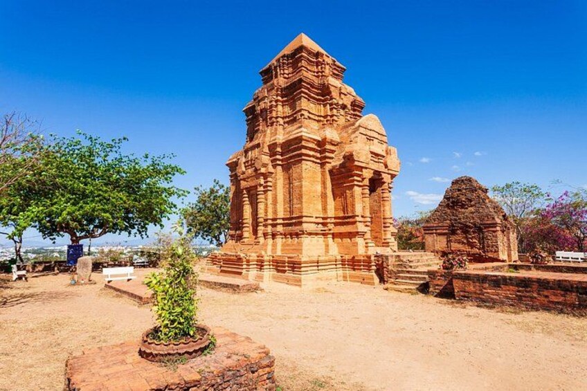 Un templo grande y antiguo con intrincados grabados, rodeado de árboles y un cielo azul despejado. 3