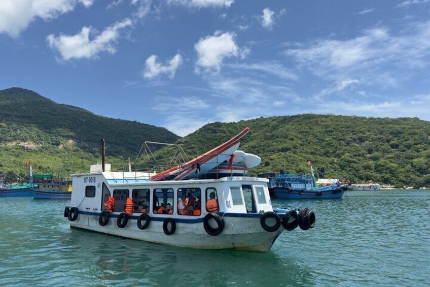 A boat with passengers, a mountainous backdrop, and calm water. 3