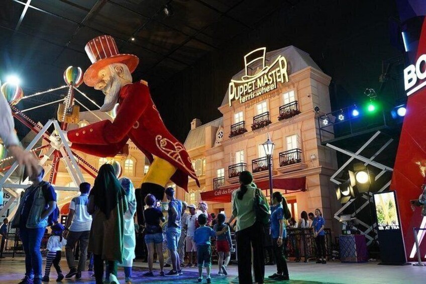 A large red puppet character, a Ferris wheel, and a building with 'PUPPET MASTER' signage. 3