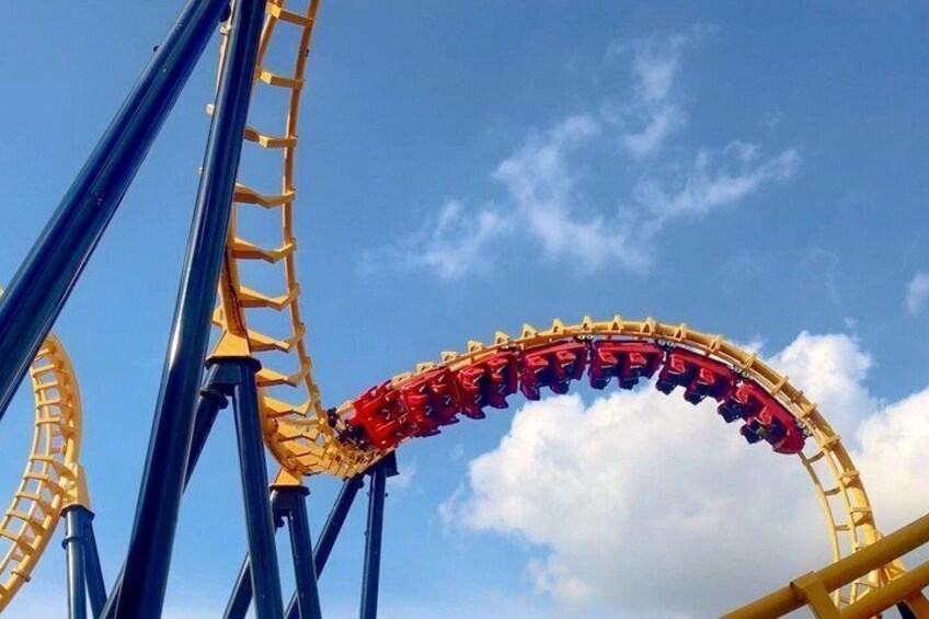 A roller coaster in mid-loop with blue and yellow tracks against a clear sky. 2