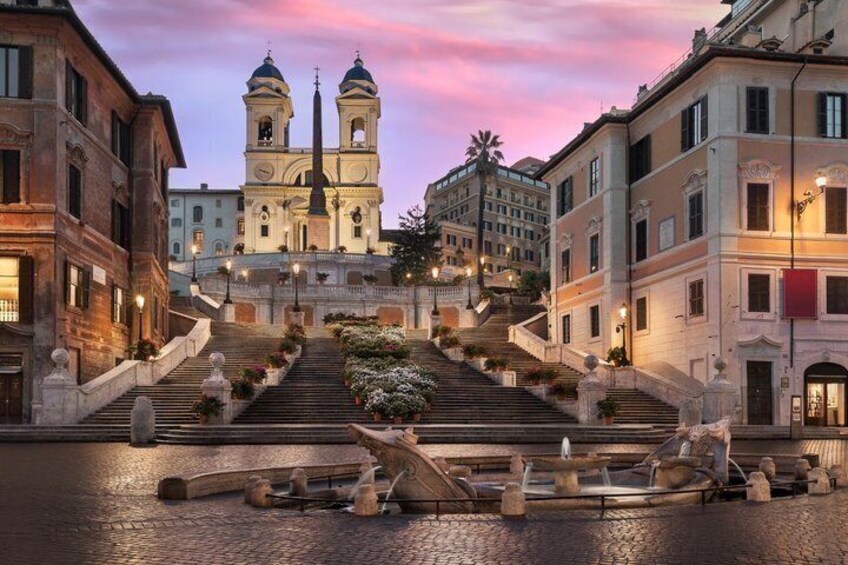 A historic square with a church, steps leading up to it, and a fountain. 3