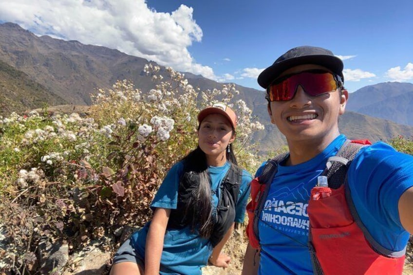 Two people sitting on a mountain with cotton plants and a clear sky. 3