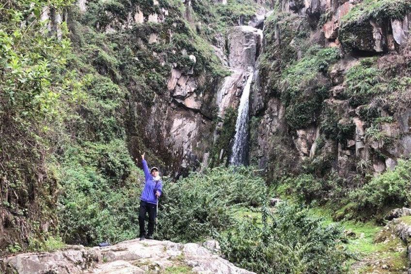 A person standing on a rock with a waterfall in the background. 5