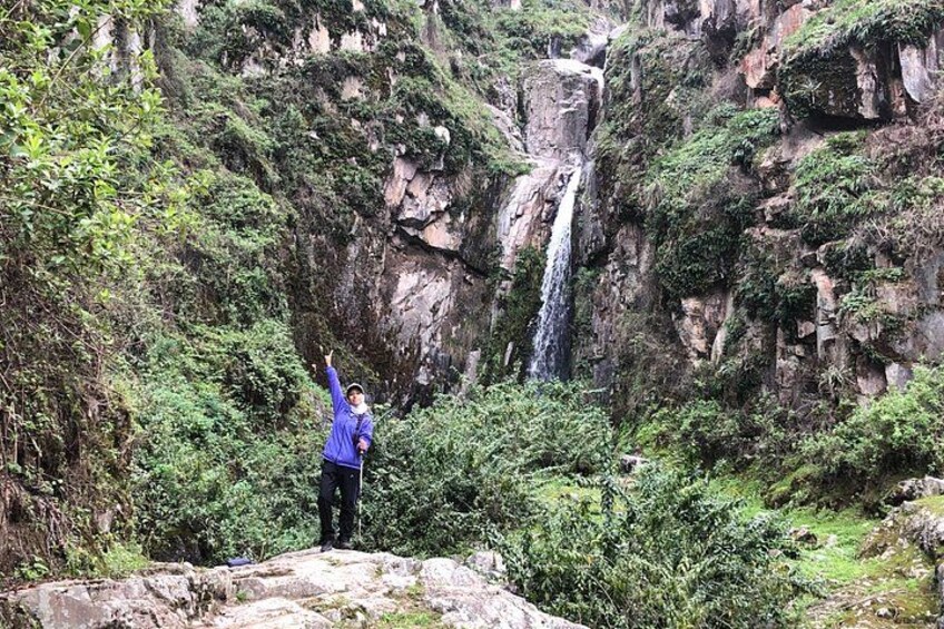 A person standing on a rock with a waterfall in the background. 5