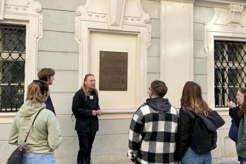 A group of people standing in front of a building with a plaque. 4