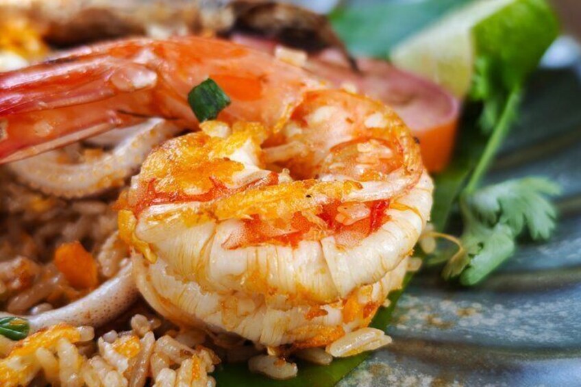 A plate of shrimp and rice garnished with herbs. 4