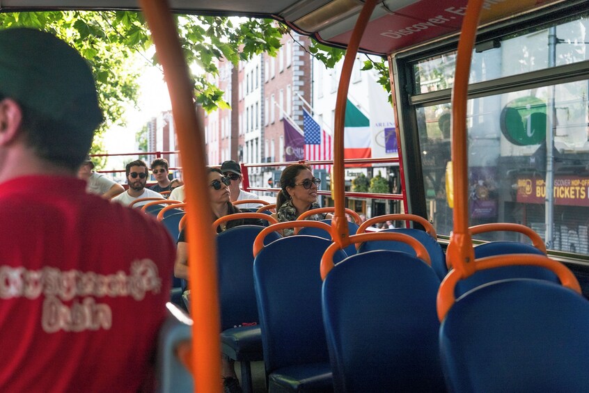 A bus interior with blue seats and an orange handrail. 1