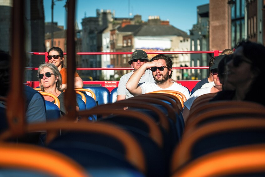 People seated in a bus with a cityscape in the background. 3