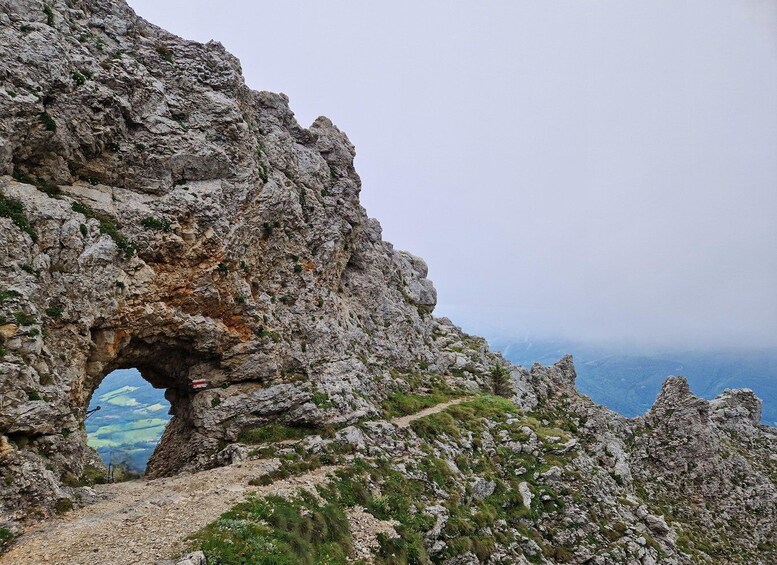 A rugged mountain landscape with a prominent rock arch formation. 2