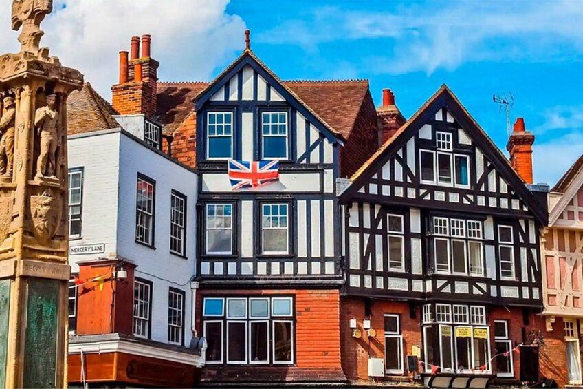Un edificio de estilo Tudor tradicional con una bandera británica, un edificio blanco con un letrero y una estatua de piedra. 4