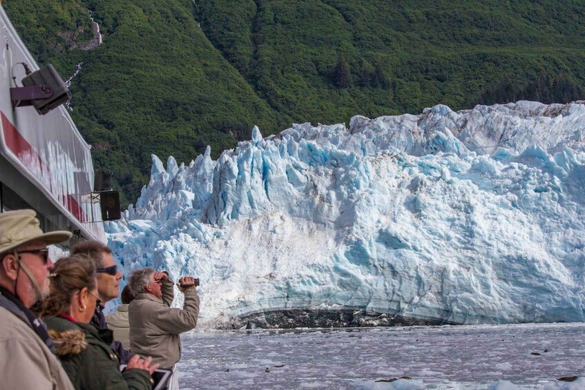 A glacier with people observing it from a boat. 1