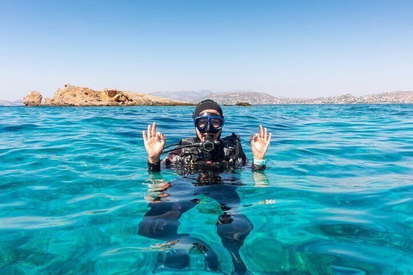 Una persona haciendo buceo en agua azul cristalina, con una costa rocosa al fondo. 3