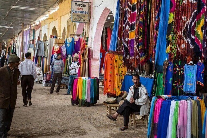 A market with colorful textiles and a sign that reads 'Marché des Caravanes.' 3