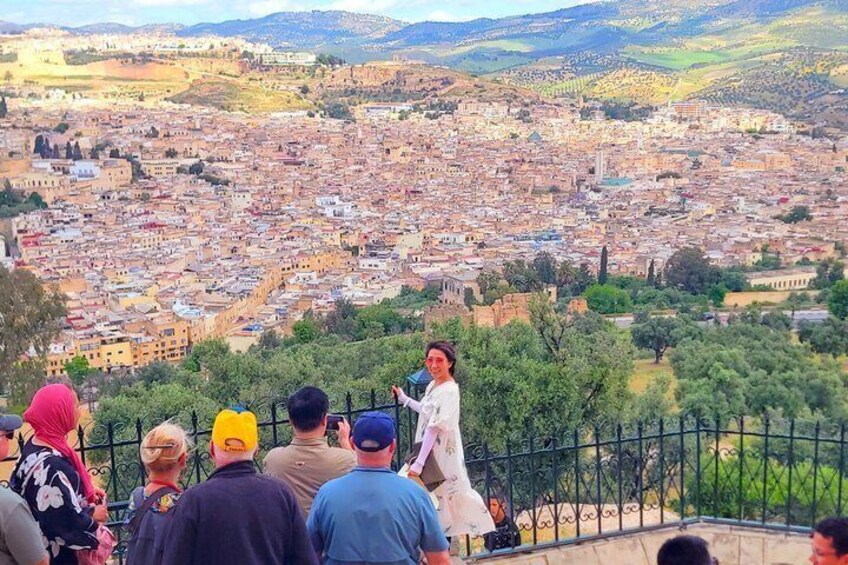 Una persona dando una presentación a un grupo de personas en un balcón con vistas a un paisaje urbano. 3