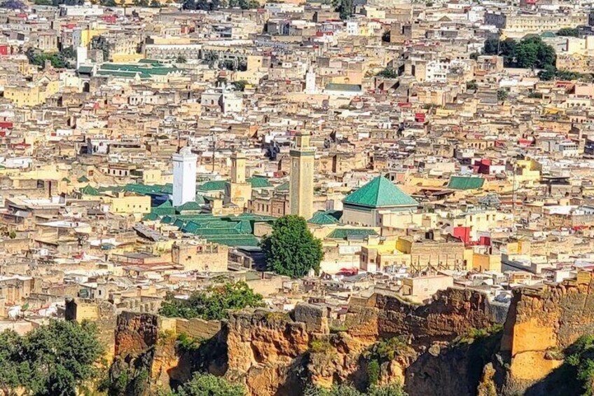Un paisaje urbano denso con edificios históricos, un minarete destacado y una gran estructura con techo verde. 4