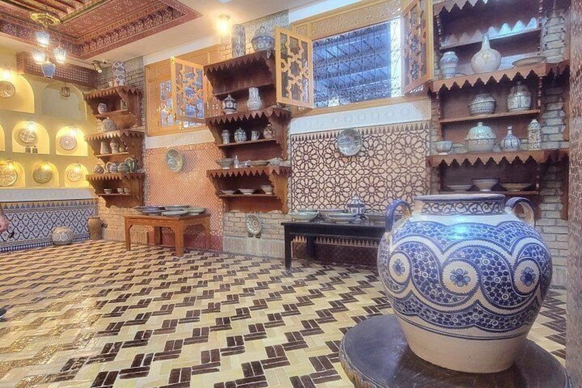 A traditional Moroccan interior with patterned tiles, shelves with pottery, and a large blue and white vase. 2
