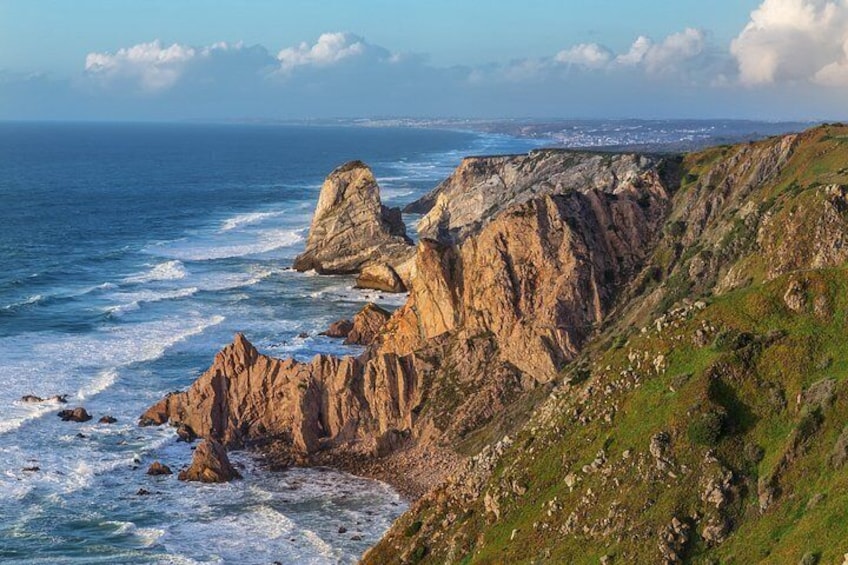 A coastal landscape with rocky cliffs, waves crashing against the shore, and a distant view of a city skyline. 4