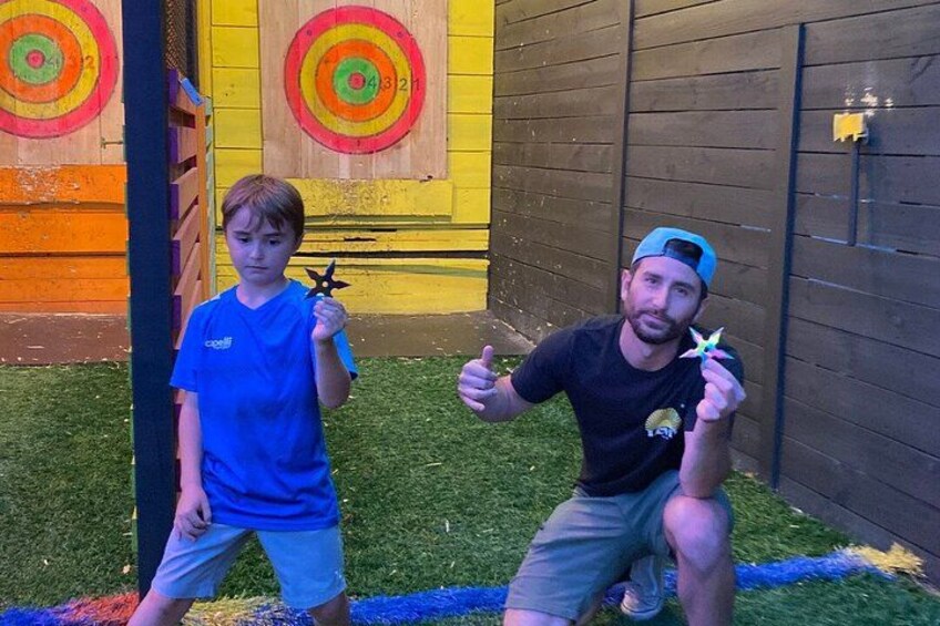 Two people holding star-shaped objects in front of a target board. 2
