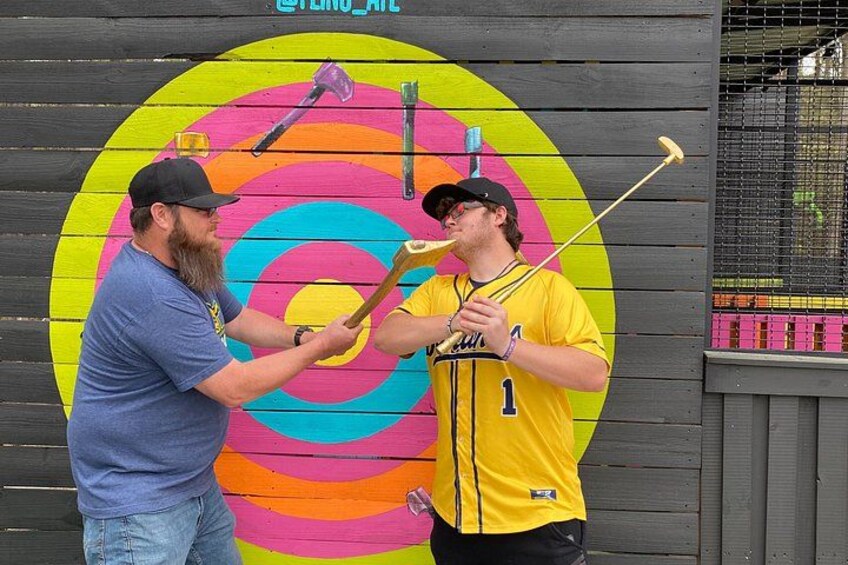 Two people playing a game with a colorful target and various tools. 5