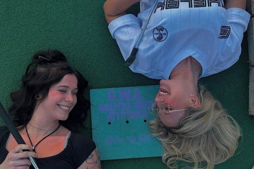 Two people lying on a green surface with a sign that reads 'CWA WATER RESOURCES'. 5