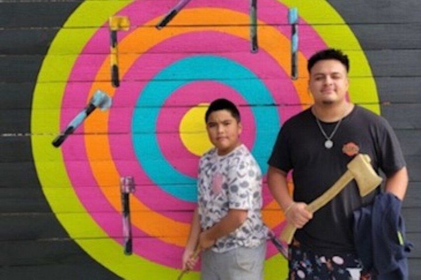 Two people standing in front of a colorful target with concentric circles. 4