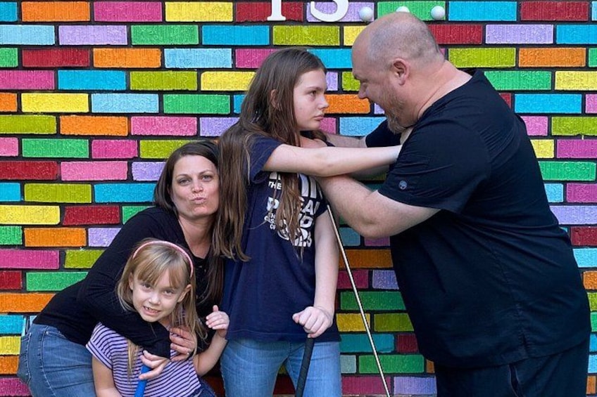 A family of four in front of a colorful brick wall. 5