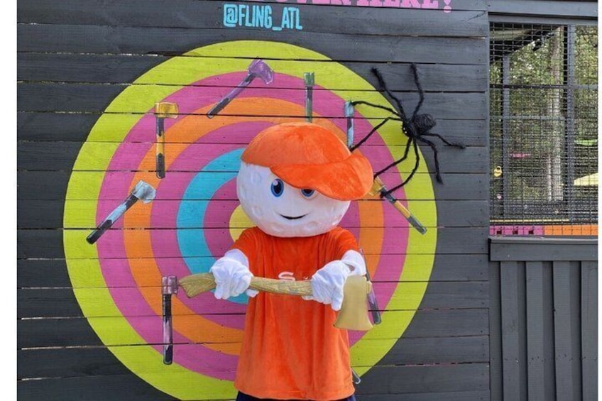 A person in a pumpkin costume standing in front of a colorful target mural. 2