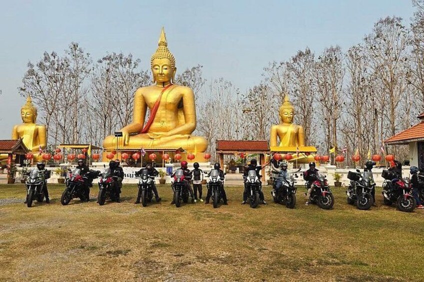 Large golden Buddha statues, motorcycles lined up in front, and leafless trees in the background. 3