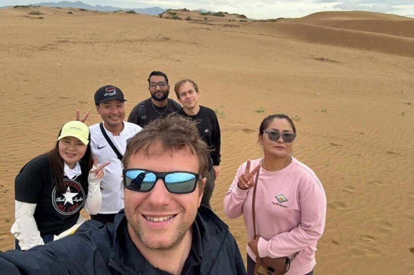 A group of people in a desert with sand dunes in the background. 1