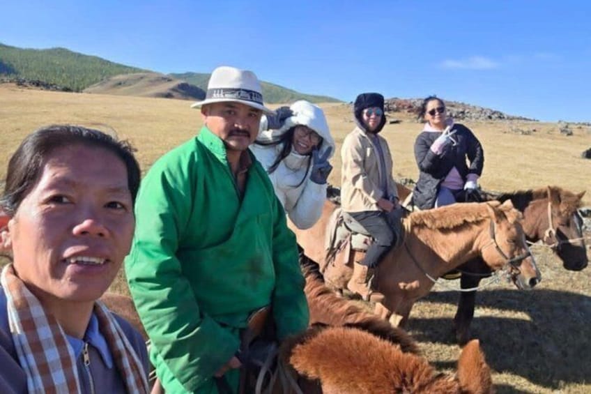 Un grupo de personas con caballos en un campo de hierba con colinas al fondo. 5